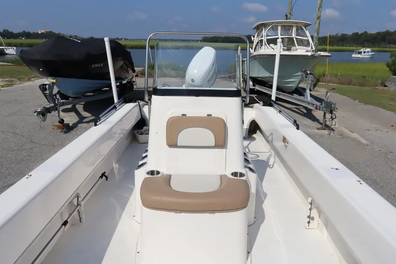 Slide: The Image of 2022 Sundance DX22 boat on trailer, parked near water with other boats. - 11