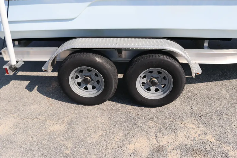 Slide: The Image of Trailer wheels of a 2022 Sundance DX22 boat on a gravel surface. - 16