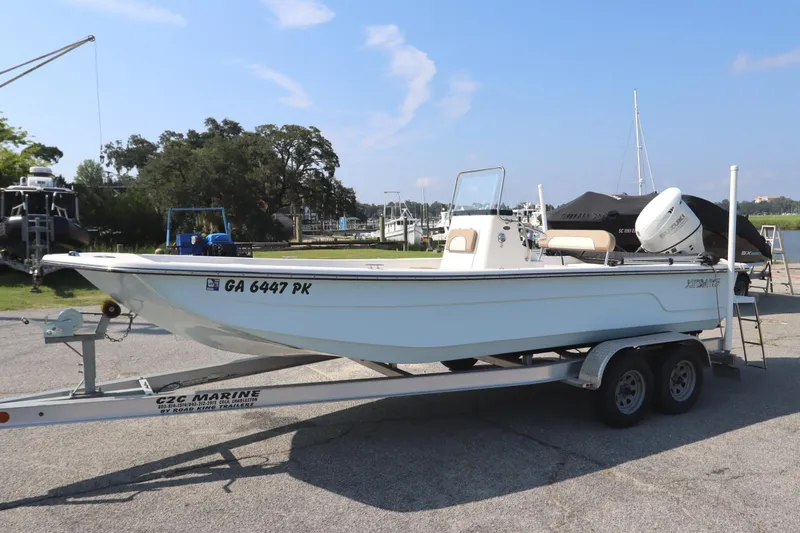Slide: The Image of 2022 Sundance DX22 boat on trailer at marina, clear sky background. - 2