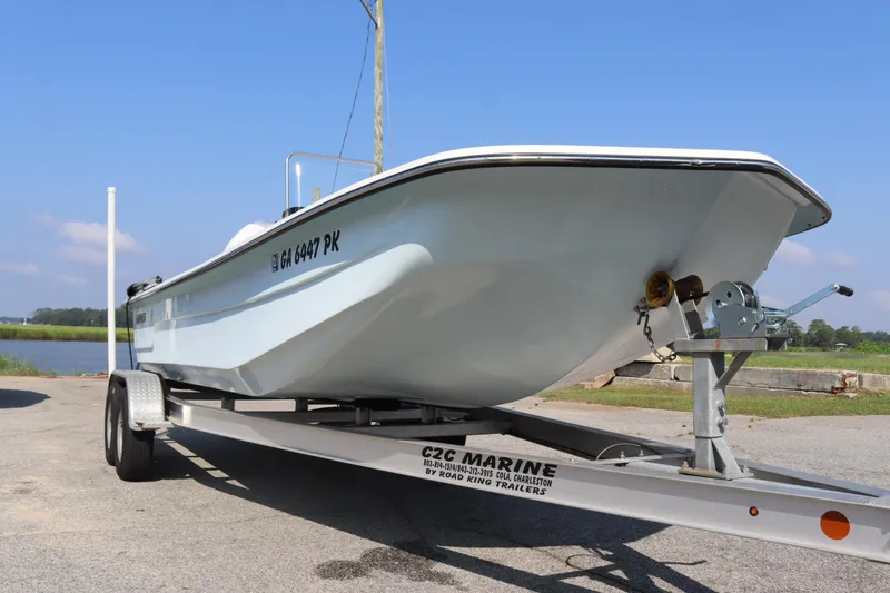 Slide: The Image of 2022 Sundance DX22 boat on trailer, parked near a scenic waterfront. - 3