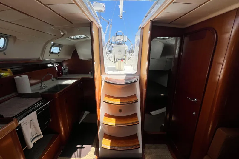 Slide: The Image of Interior of 1996 Beneteau Oceanis 400 sailboat, featuring wooden cabinetry and compact kitchen area. - 18