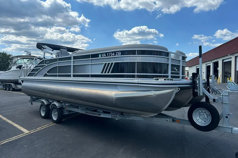 Slide: The Image of 2023 Bennington L 23 Swingback pontoon boat on trailer under a partly cloudy sky. - 3