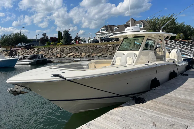 The Image of 2026 Scout 330 LXF boat docked at marina under blue sky. - 0