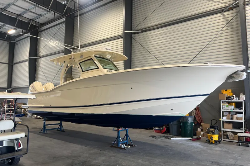 Slide: The Image of 2026 Scout 330 LXF boat in a warehouse, elevated on stands. - 11