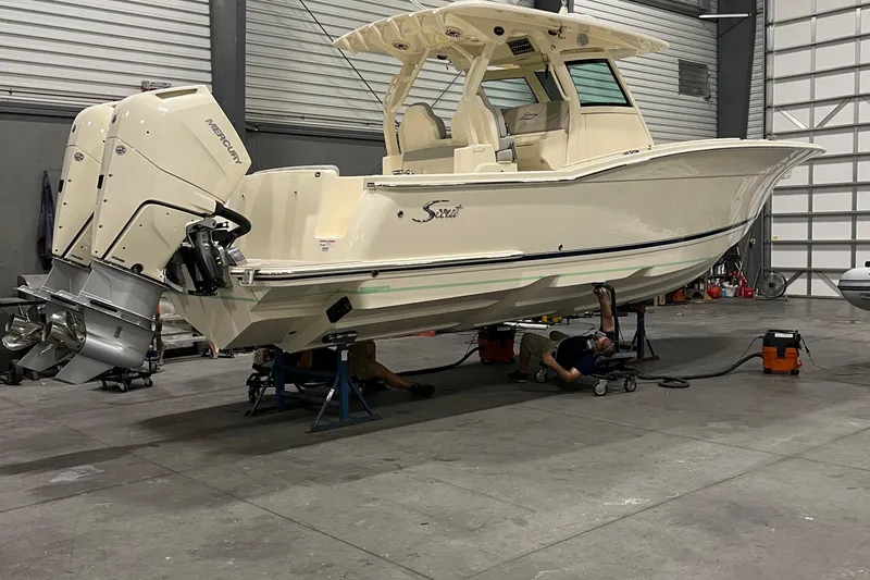 Slide: The Image of 2026 Scout 330 LXF boat in a workshop with dual Mercury outboard engines. - 12