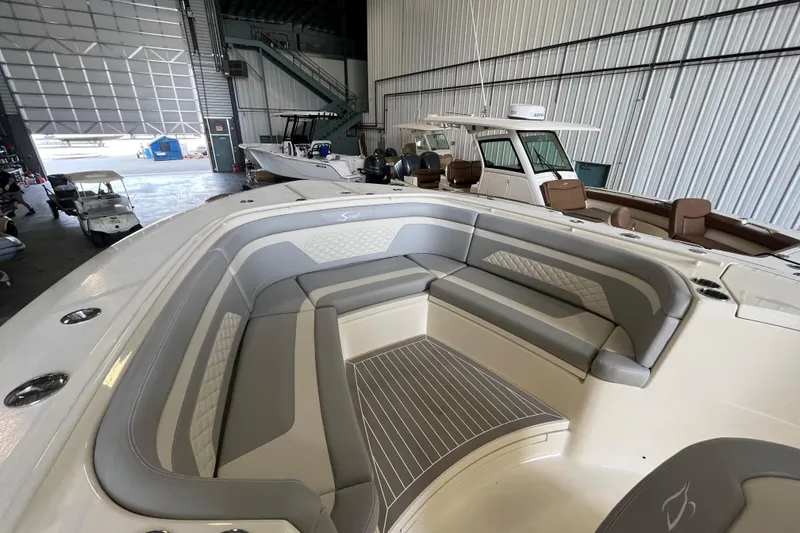 Slide: The Image of 2026 Scout 330 LXF boat interior with gray seating in a storage facility. - 21