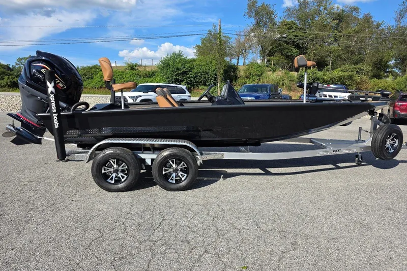 The Image of 2026 Xpress X19 Pro boat on trailer, black exterior, parked outdoors under blue sky. - 1