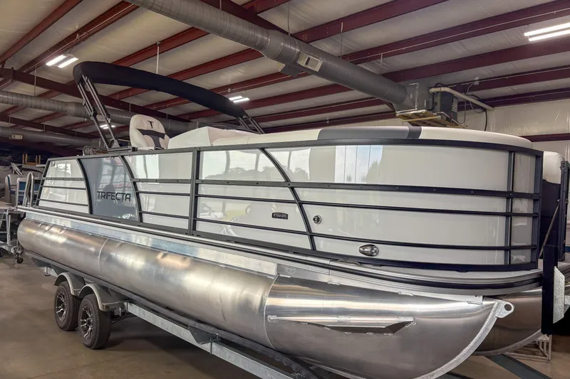 The Image of 2026 Trifecta 24UL CS pontoon boat in a warehouse, showcasing sleek design and modern features. - 1