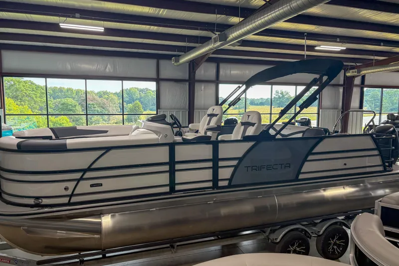 Slide: The Image of 2026 Trifecta 24UL CS pontoon boat in a showroom, featuring sleek design and modern seating. - 4