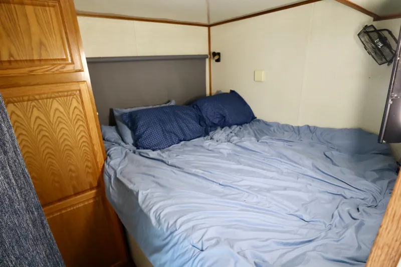 Slide: The Image of Cozy bedroom in 1997 Fun Country Forerunner RV with blue bedding and wooden cabinets. - 15