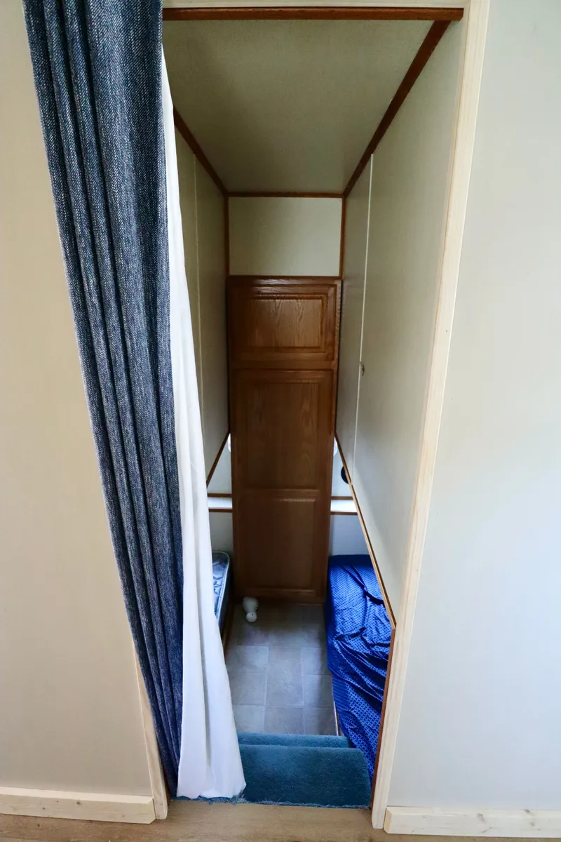 Slide: The Image of Narrow hallway with wooden cabinet, blue curtain, and flooring in a 1997 Fun Country Forerunner. - 22