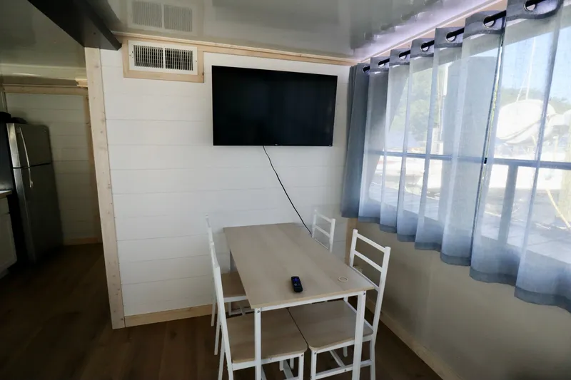 Slide: The Image of Small dining area with table, chairs, wall-mounted TV, and large window with curtains. - 32