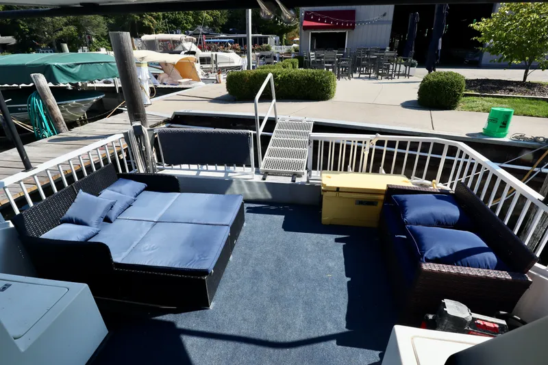Slide: The Image of Houseboat deck with blue cushioned seating, yellow storage box, and marina view. Fun Country Forerunner 1997. - 44