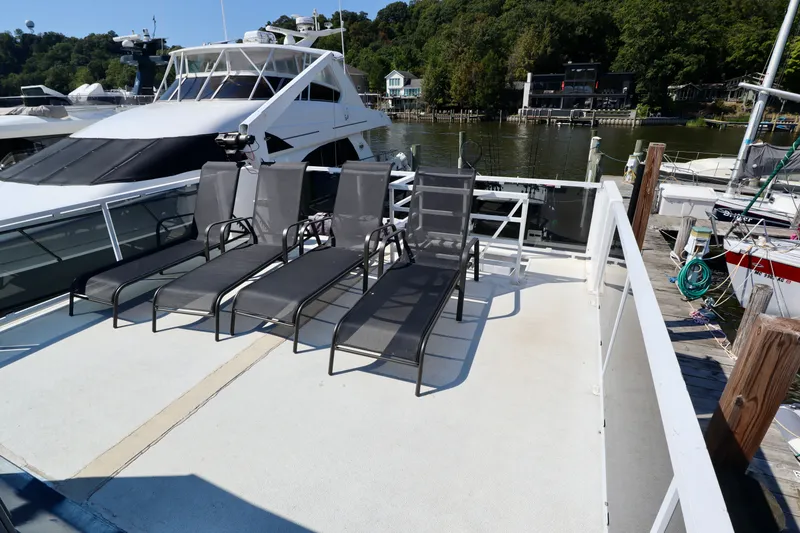 Slide: The Image of Rooftop deck of 1997 Fun Country Forerunner with lounge chairs, docked by a scenic waterfront. - 8