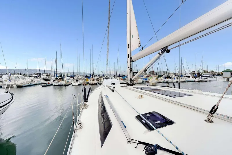 Slide: The Image of 2016 Bavaria 51 Cruiser yacht docked in a marina, surrounded by sailboats under a clear blue sky. - 1