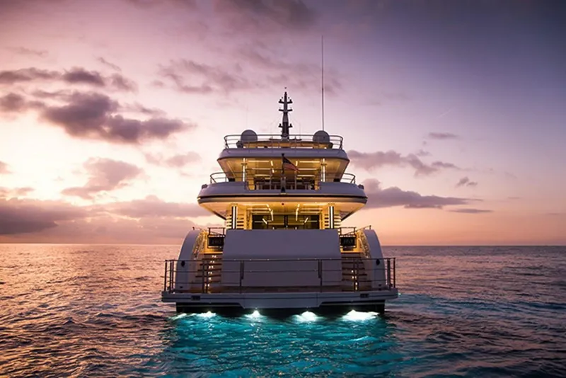 Slide: The Image of Majesty 140 yacht at sunset, 2020 model, illuminated on calm ocean waters. - 10