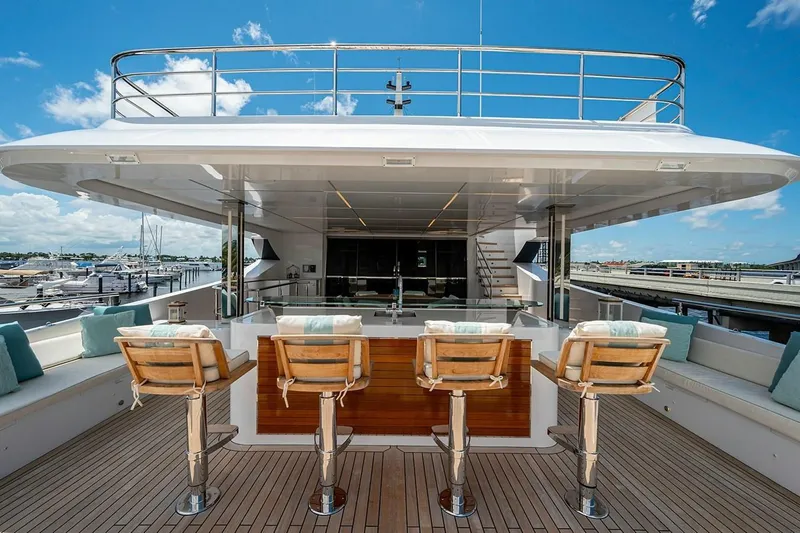 Slide: The Image of Luxury Majesty 140 yacht deck with bar stools, 2020 model, under clear blue sky. - 19