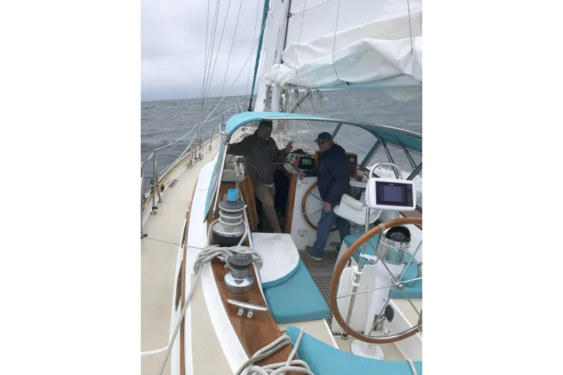 Slide: The Image of 1984 Shannon 51' Center Cockpit sailboat with two people navigating on open sea. - 4