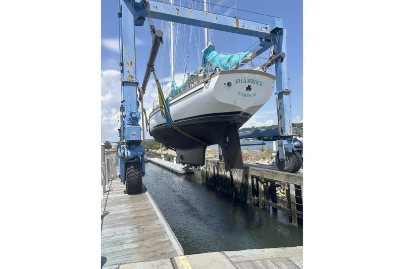 Slide: The Image of 1984 Shannon 51' Center Cockpit sailboat lifted by a boat hoist at a marina. - 5
