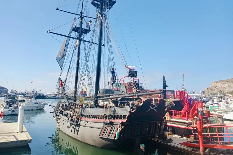 Slide: The Image of Custom 1977 Brigantine ship docked in a marina, with crew members on deck. - 1