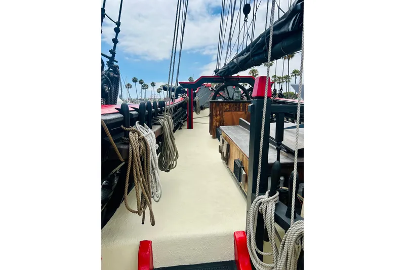 Slide: The Image of 1977 Custom Brigantine ship deck with ropes and rigging, under a partly cloudy sky. - 19