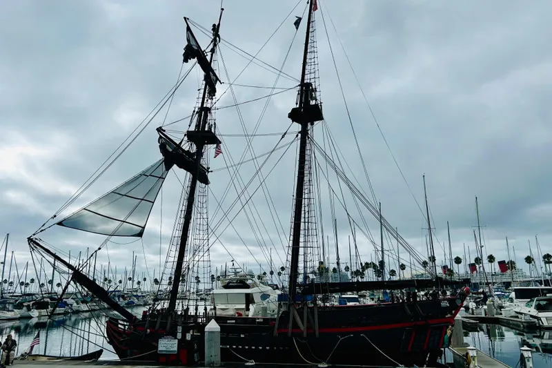 Slide: The Image of Vintage 1977 Custom Brigantine ship docked at a marina under cloudy skies. - 3