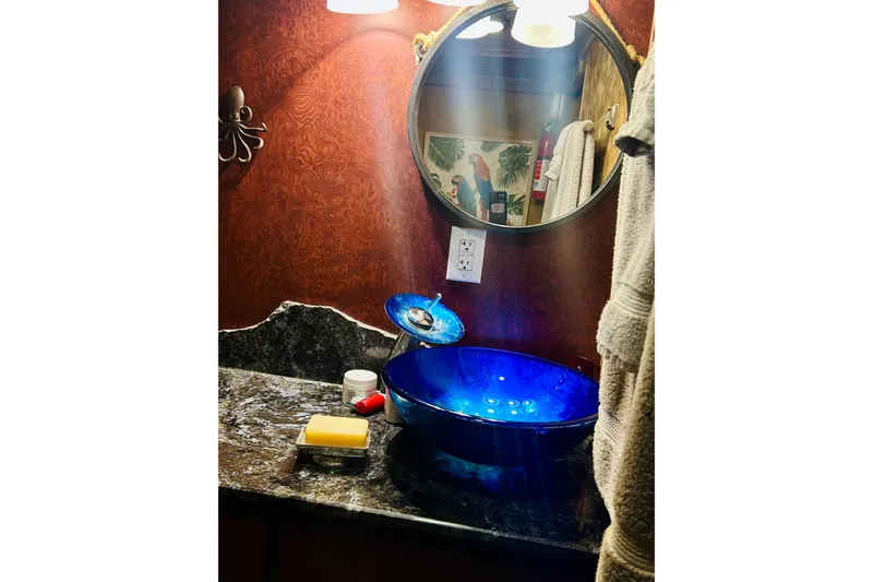Slide: The Image of Luxurious bathroom with blue glass sink, ornate mirror, and elegant red wallpaper. - 31