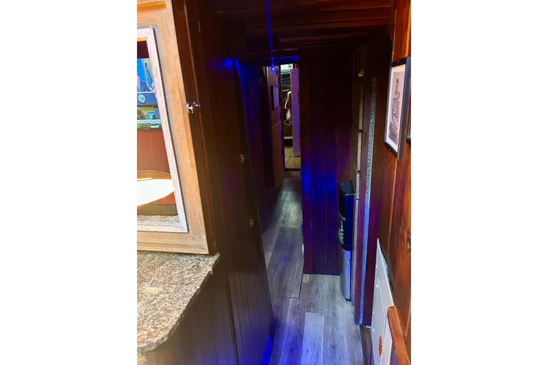 Slide: The Image of Narrow wooden hallway inside a 1977 Custom Brigantine boat with blue lighting. - 35