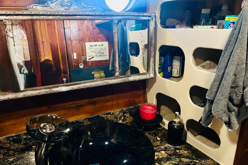 Slide: The Image of Vintage 1977 Custom Brigantine bathroom with ornate mirror, black sink, and storage shelves. - 37