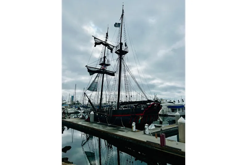 Slide: The Image of Vintage 1977 Custom Brigantine ship docked at marina under cloudy sky. - 4