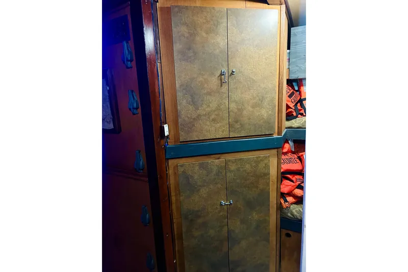 Slide: The Image of Wooden cabinets inside a 1977 Custom Brigantine boat, with life jackets stored nearby. - 50