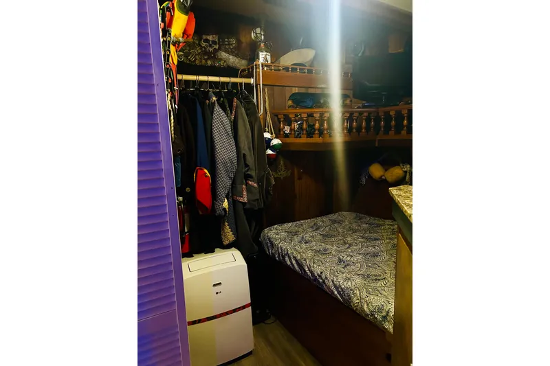 Slide: The Image of Cozy cabin interior of a 1977 Custom Brigantine with clothes, bed, and portable air conditioner. - 52