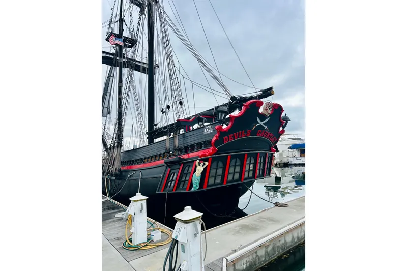 Slide: The Image of Vintage 1977 Custom Brigantine ship "Devil's Gauntlet" docked at marina, featuring pirate-themed design. - 6