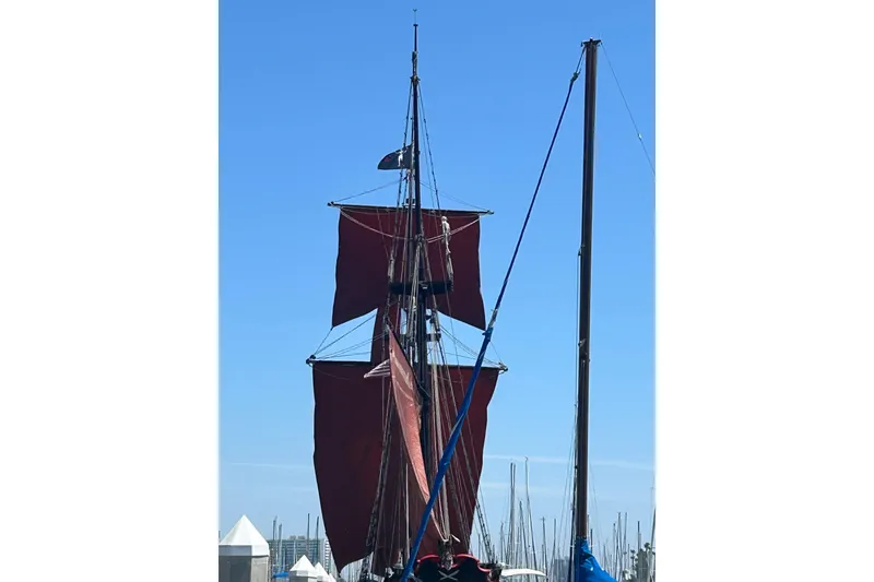 Slide: The Image of Vintage 1977 Custom 80 Brigantine sailboat with red sails against a clear blue sky. - 4