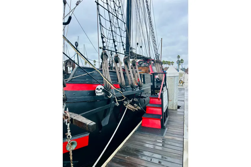 Slide: The Image of Vintage 1977 Custom Brigantine ship docked, featuring red accents and skull decoration. - 9