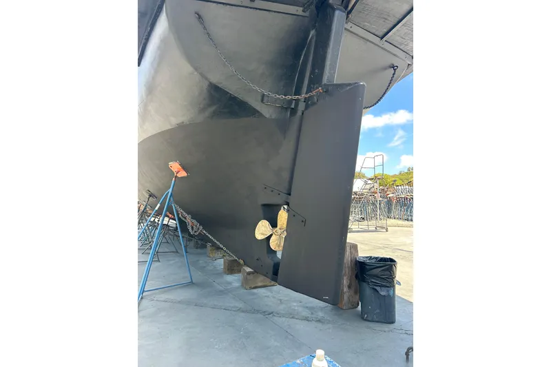 Slide: The Image of Bottom view of a 1977 Custom 80 Brigantine sailboat in dry dock, showing the rudder and propeller. - 64
