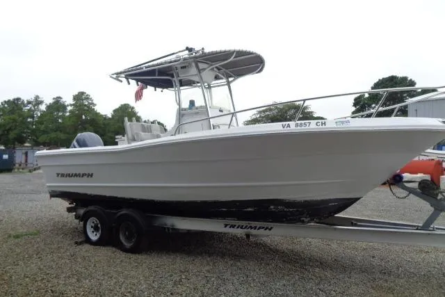 Slide: The Image of 2008 Triumph 235 CC boat on trailer, side view, parked outdoors. - 3