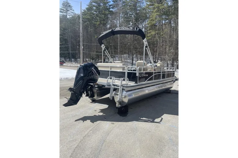 Slide: The Image of 2024 Lowe Ultra 202 Fish & Cruise pontoon boat with Mercury outboard motor, parked outdoors. - 2