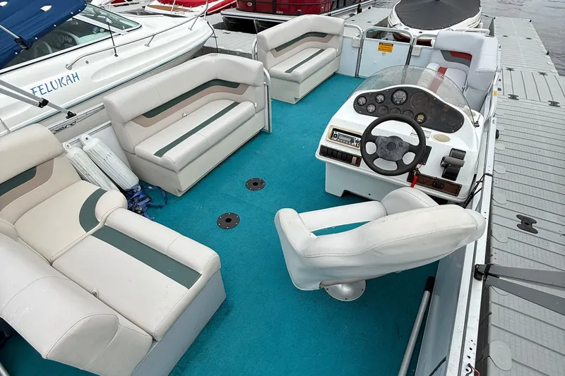 Slide: The Image of 1998 AquaPatio 210RS pontoon boat with white seating and blue carpet at dock. - 4