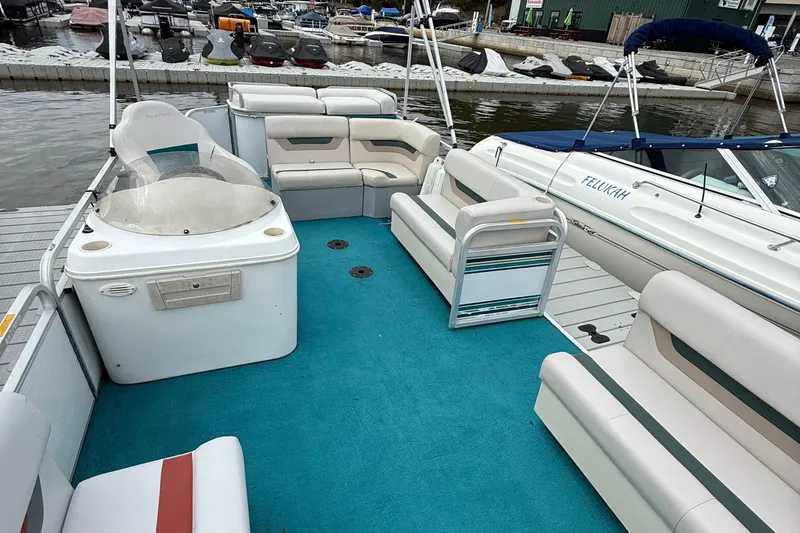 Slide: The Image of 1998 AquaPatio 210RS pontoon boat with blue carpet and white seating at a marina. - 5
