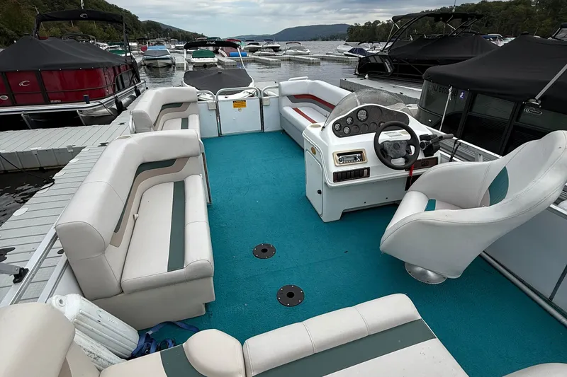 Slide: The Image of 1998 AquaPatio 210RS pontoon boat with blue carpet and white seating at a marina. - 7