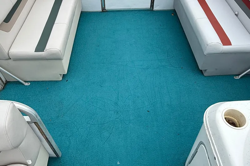 Slide: The Image of Interior of a 1998 AquaPatio 210RS boat with teal carpet and white seating. - 9