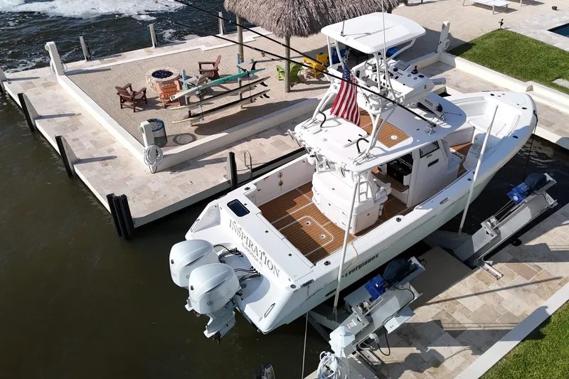 Slide: The Image of 2018 Everglades 335 Center Console boat docked by a waterfront patio. - 10