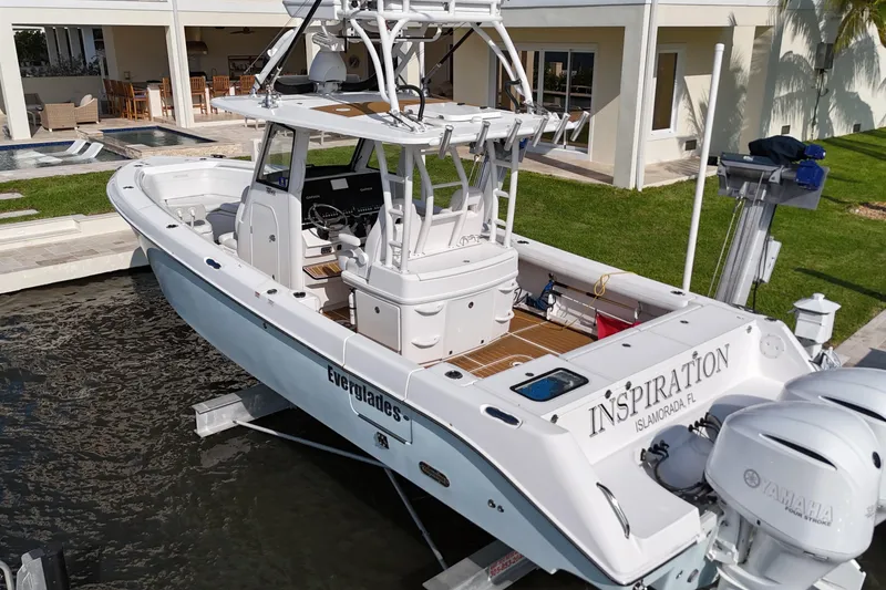 Slide: The Image of 2018 Everglades 335 Center Console boat docked near a modern waterfront home. - 11