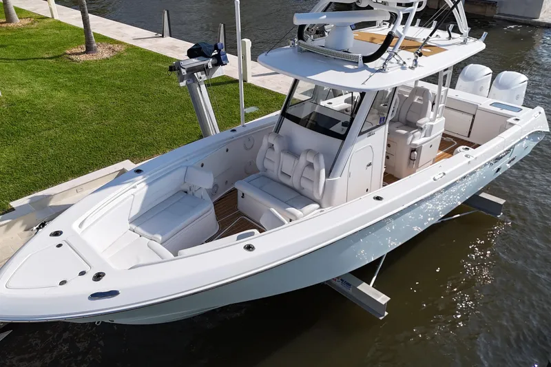 Slide: The Image of 2018 Everglades 335 Center Console boat docked by the water, showcasing sleek design and spacious seating. - 17