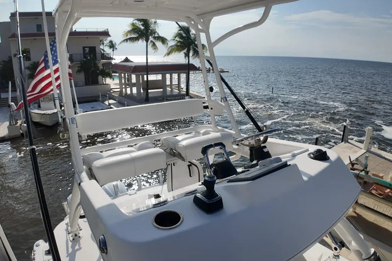 Slide: The Image of 2018 Everglades 335 Center Console boat docked by the ocean with palm trees. - 18