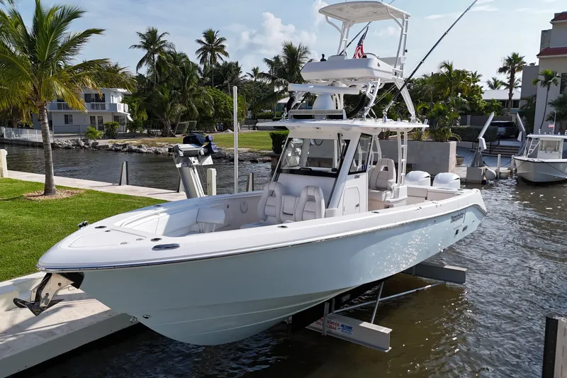 Slide: The Image of 2018 Everglades 335 Center Console boat docked by palm trees and waterfront homes. - 34