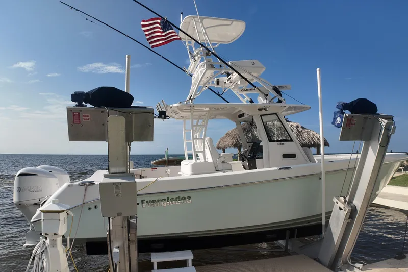 Slide: The Image of 2018 Everglades 335 Center Console boat docked with American flag, ocean backdrop. - 38