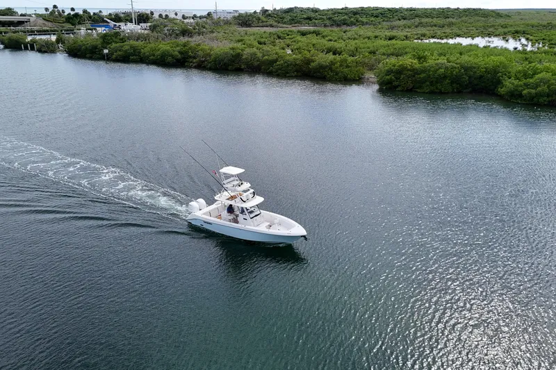 Slide: The Image of 2018 Everglades 335 Center Console boat cruising on a serene waterway near lush greenery. - 5