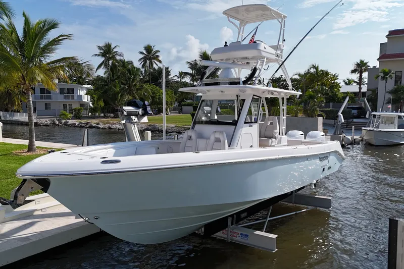 Slide: The Image of 2018 Everglades 335 Center Console boat docked by palm trees and waterfront homes. - 7